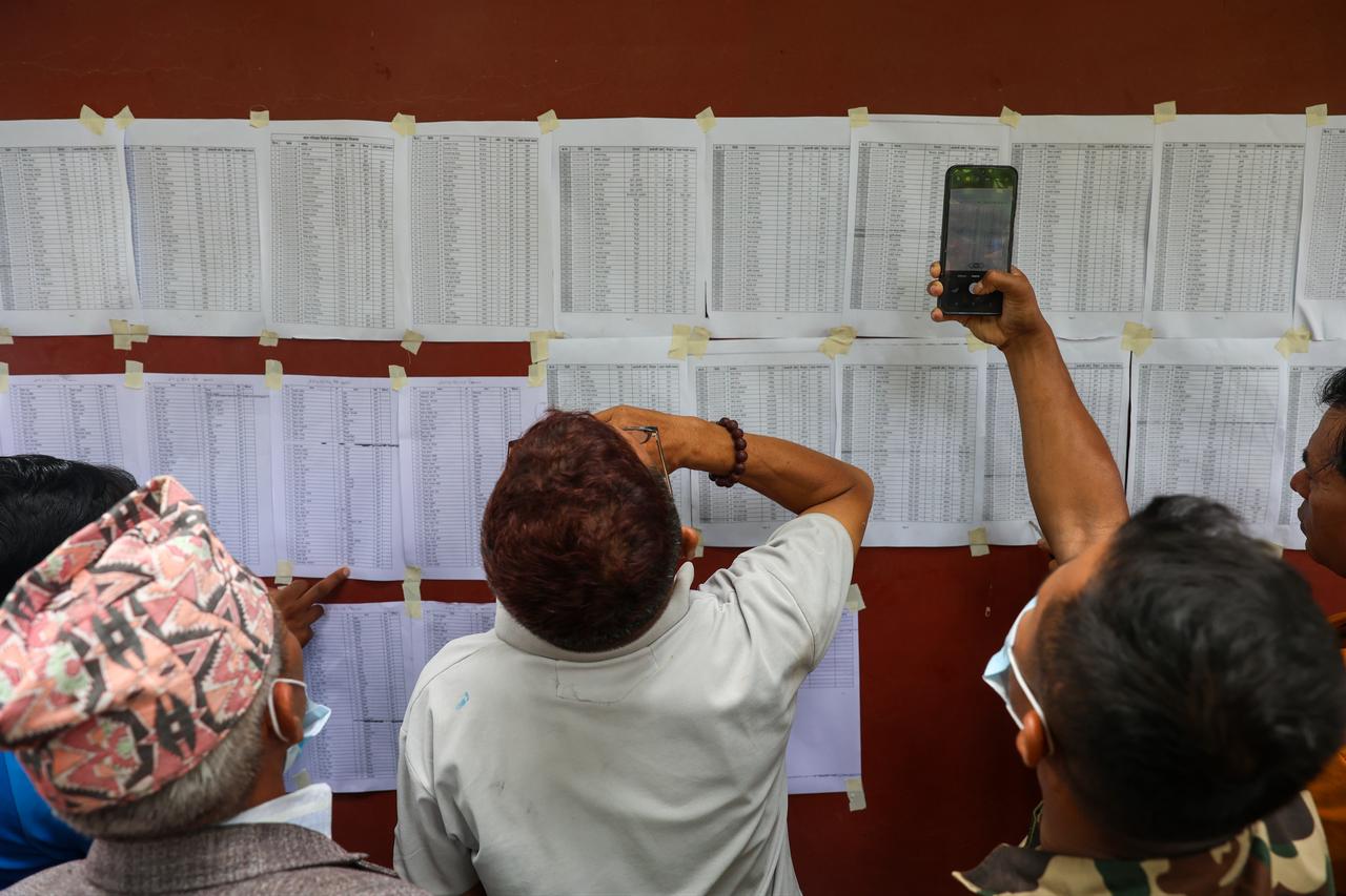 People examine and photograph posted lists as authorities account for victims and missing people following flash floods in Nepal, Aug. 29, 2026. (AA Photo)