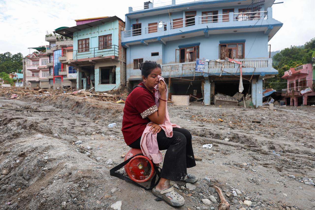 A man holds a child while looking toward the Trishuli River from higher ground after residents fled their homes following a new flash flood warning in Bidur, Nuwakot district, Nepal, Aug. 30, 2026. (AA Photo)