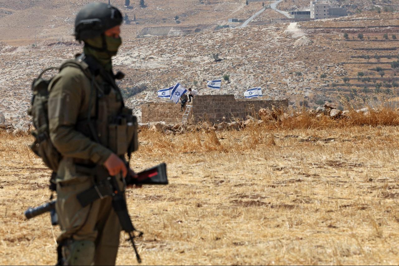 An Israeli soldier stands against the backdrop of a house seized by Israeli illegal settlers in Beit Sahur, south of Bethlehem, in the occupied West Bank on August 14, 2026. (AFP Photo)