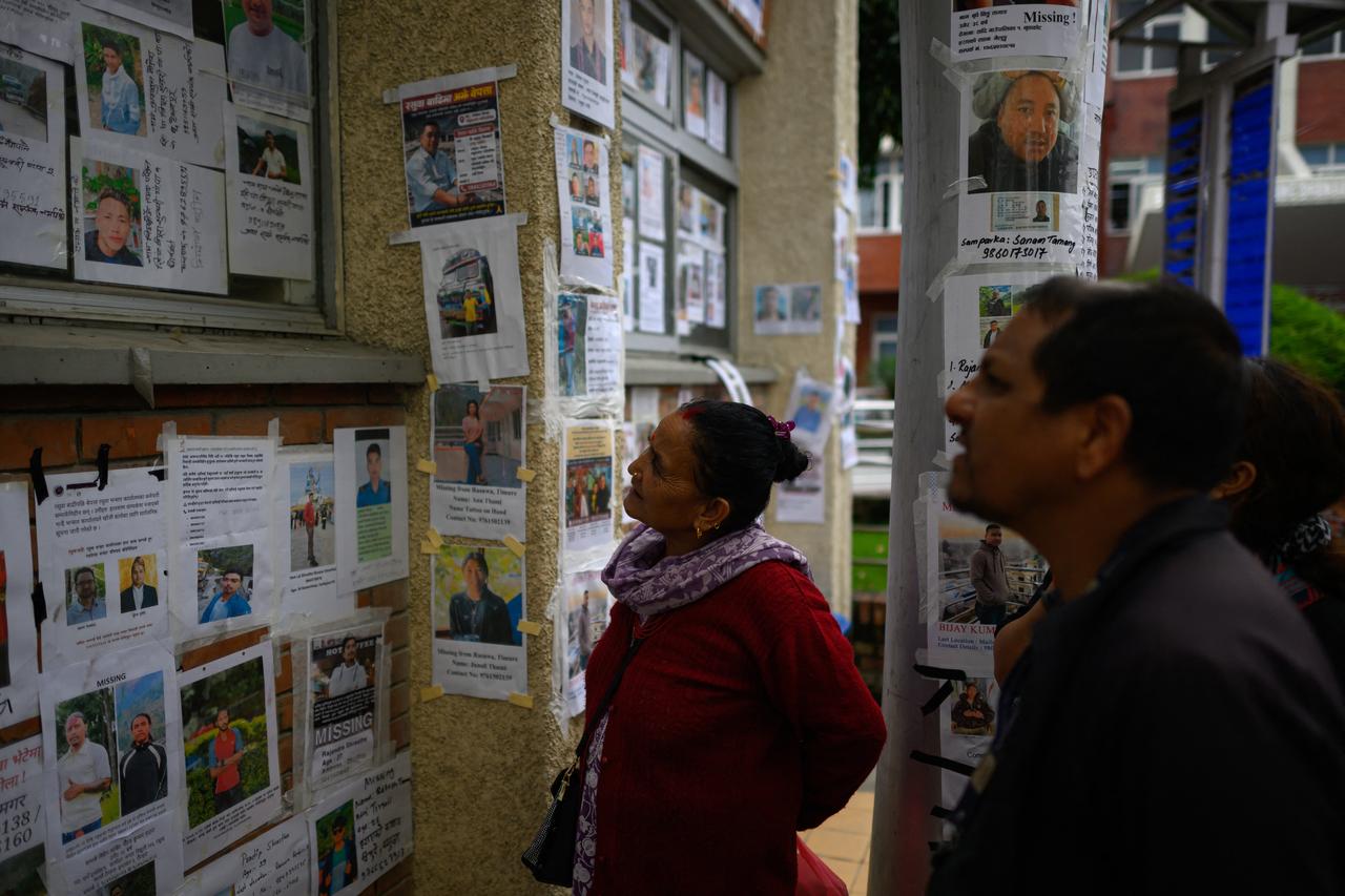 Relatives look at photographs of missing persons in the aftermath of flash floods at the Tribhuvan University Teaching Hospital in Kathmandu on August 31, 2026. (AFP Photo)