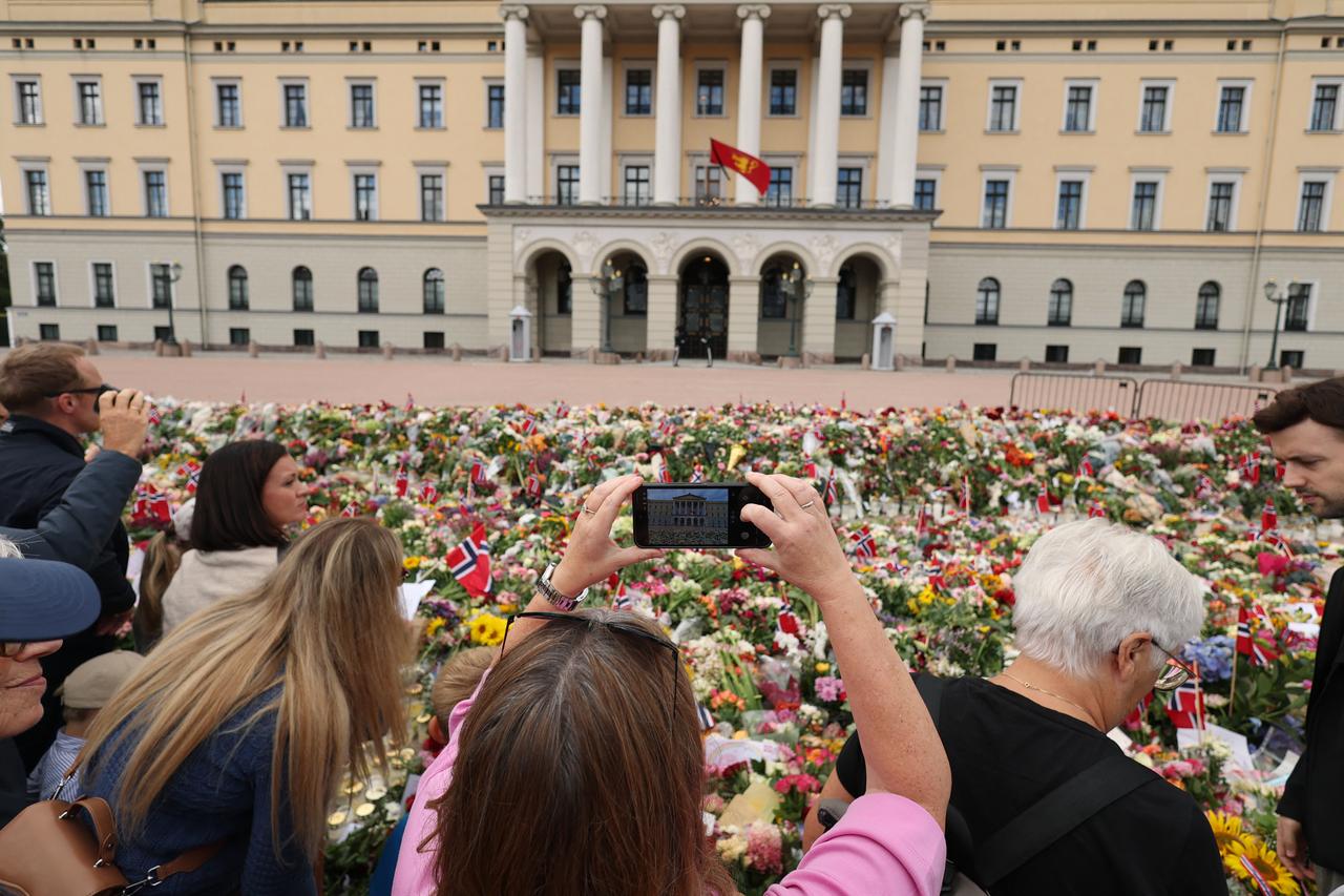 Woman taking picture of the Royal Palace behind a makeshift memorial to pay tribute to King Harald V of Norway. (AFP Photo)