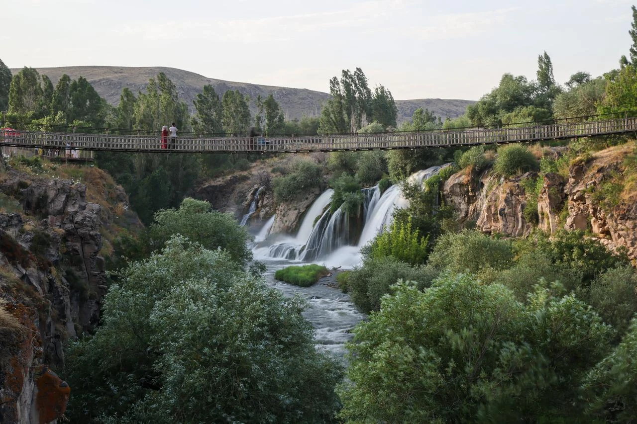 Visitors cross a suspension bridge above Muradiye Waterfall in Muradiye, Van, Türkiye, Aug. 4, 2026. (AA Photo)