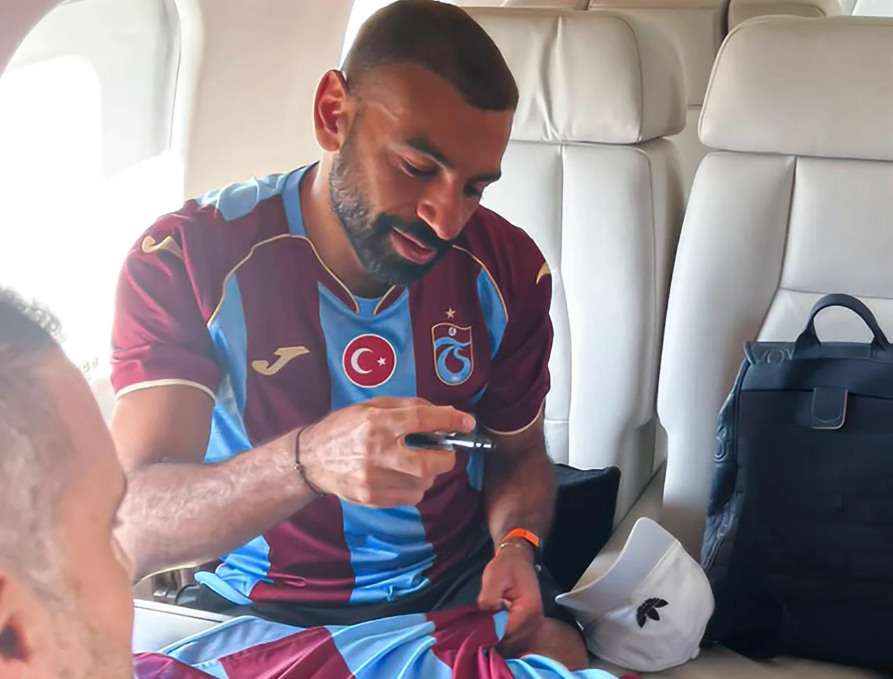 Mohamed Salah signs Trabzonspor jerseys while seated inside a private aircraft. (Photo via X/@trabzonspor)
