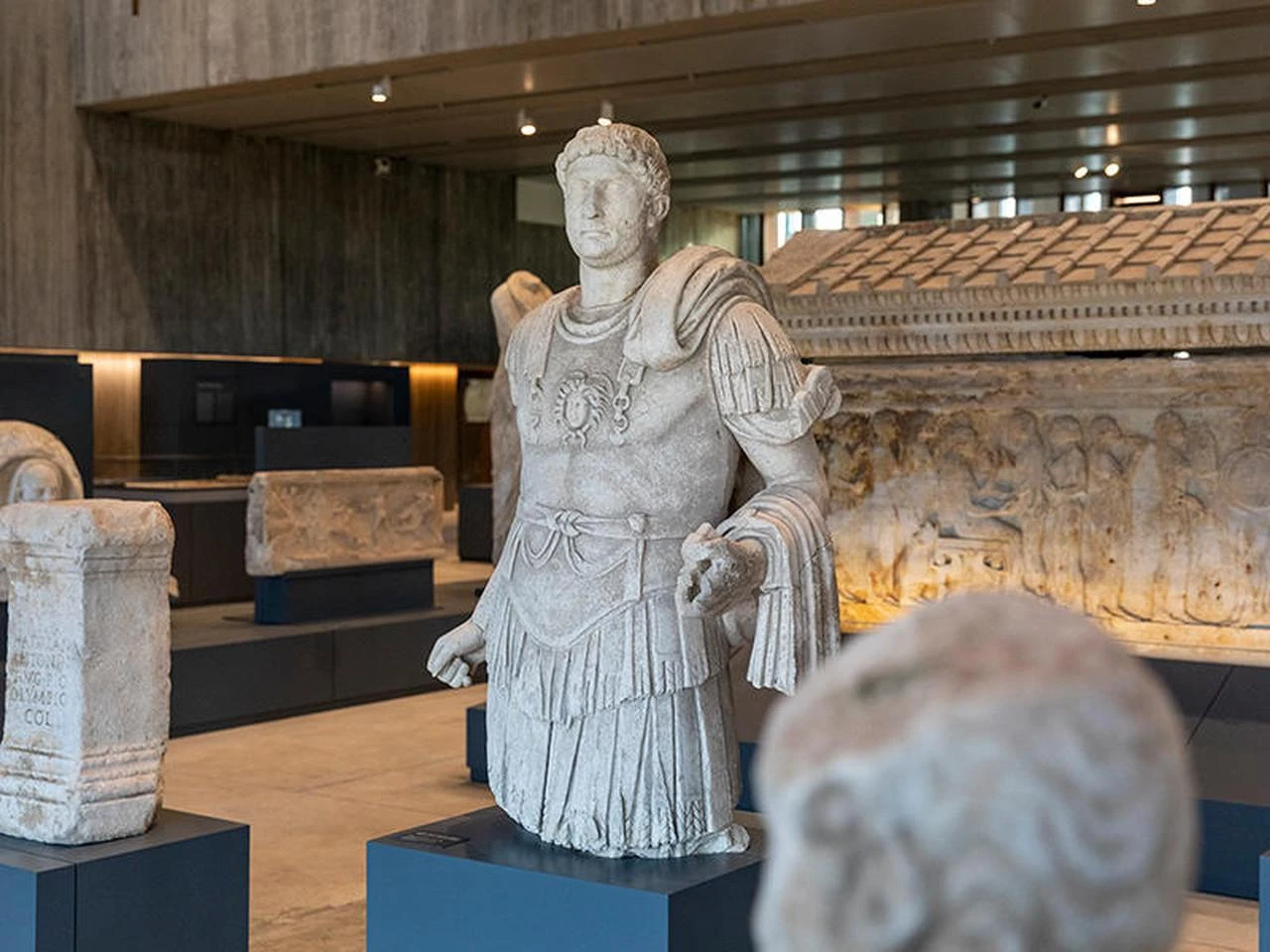A marble statue of Roman Emperor Hadrian, depicted in military dress, is displayed at the Troy Museum in Canakkale, Türkiye, with the Polyxena Sarcophagus visible in the background. (Photo via Emre Dorter)