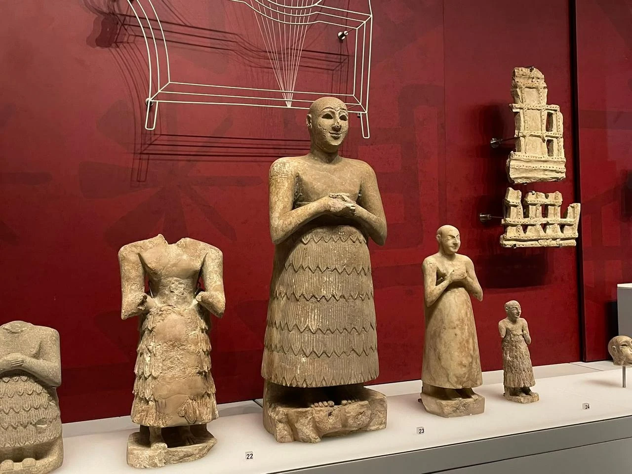 Ancient Mesopotamian votive statues and architectural models are displayed against a deep-red gallery wall at Istanbul’s Museum of the Ancient Orient, Türkiye. (Photo by Koray Erdogan/Türkiye Today)