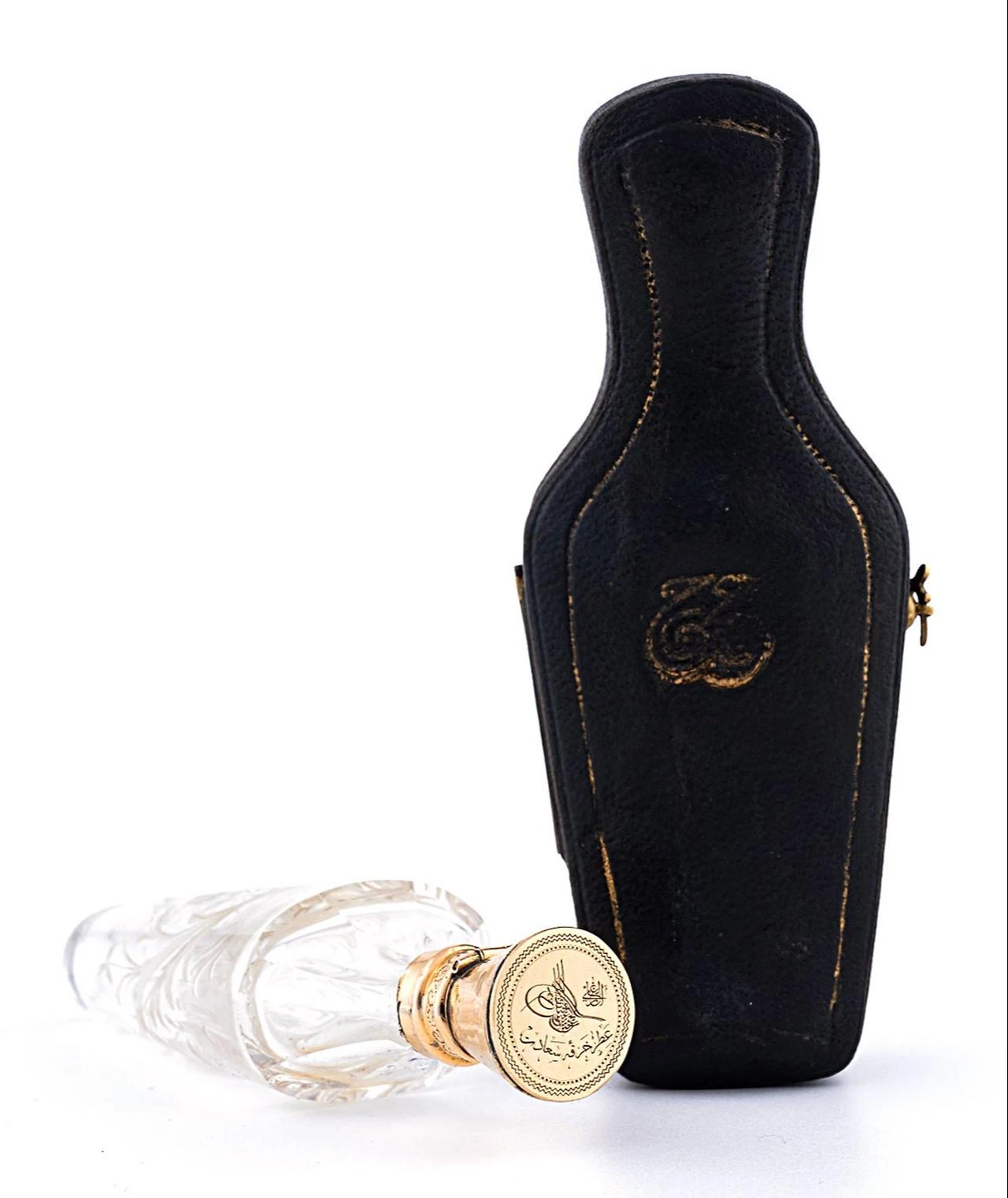 A crystal bottle and its leather case, said to have held a fragrance associated with the Holy Mantle, are among the Ottoman palace objects offered at auction. (Photo via Türkiye daily)