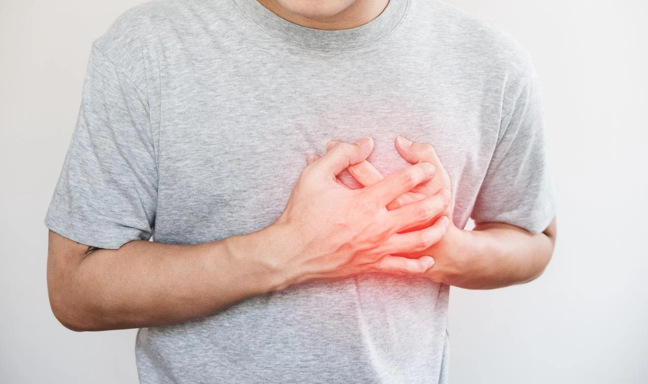 Hands holding chest with symptoms of a heart attack. (Photo via Adobe Stock)