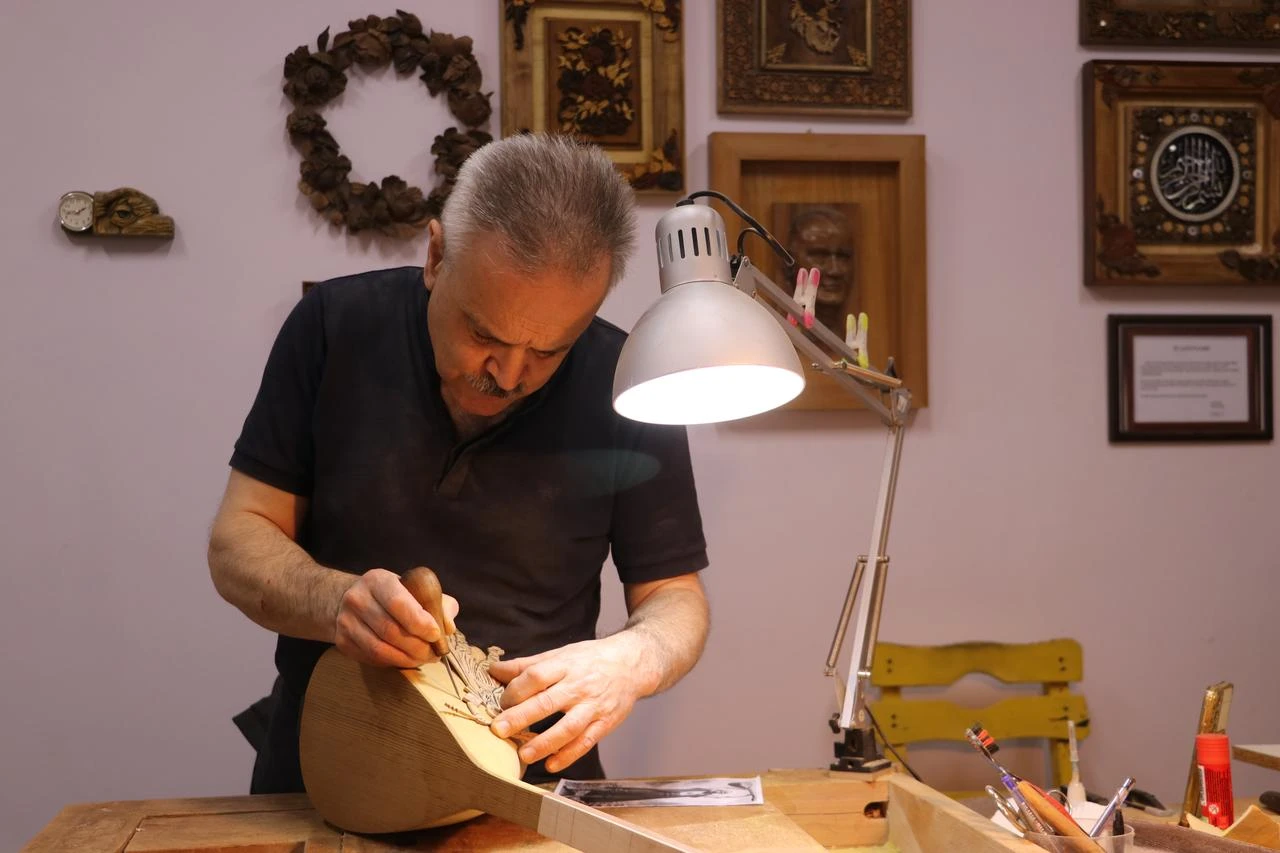 Pertev Aslan, a naht artist living in Tekirdag, carves an artist figure on a baglama. (AA Photo)
