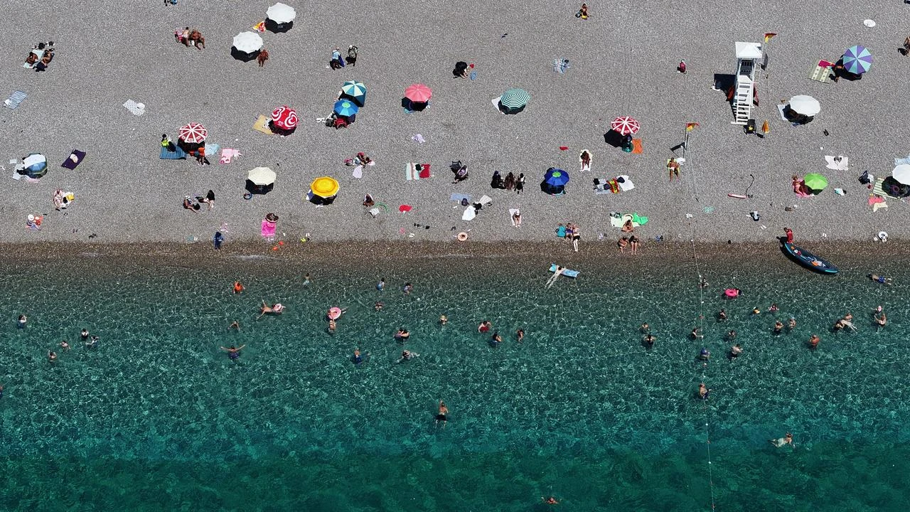 An aerial view shows people swimming and relaxing along a crowded beach in Antalya, Türkiye. (AA Photo)