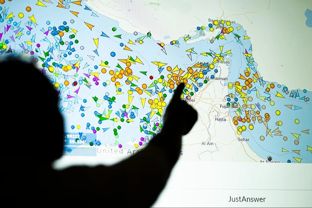 A photo illustration taken in Nicosia on May 4, 2026, shows a person in front of a large screen displaying vessel movements in the Strait of Hormuz on a ship-tracking website. (AFP Photo)