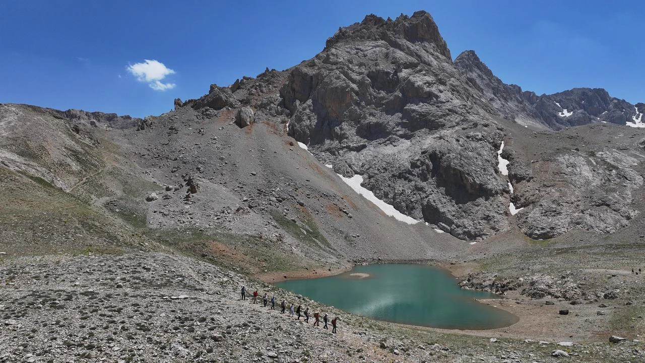 Hikers pass a glacial lake surrounded by steep rocky peaks in the Aladağlar mountain range, Nigde, Türkiye, Aug. 9, 2026. (AA Photo)