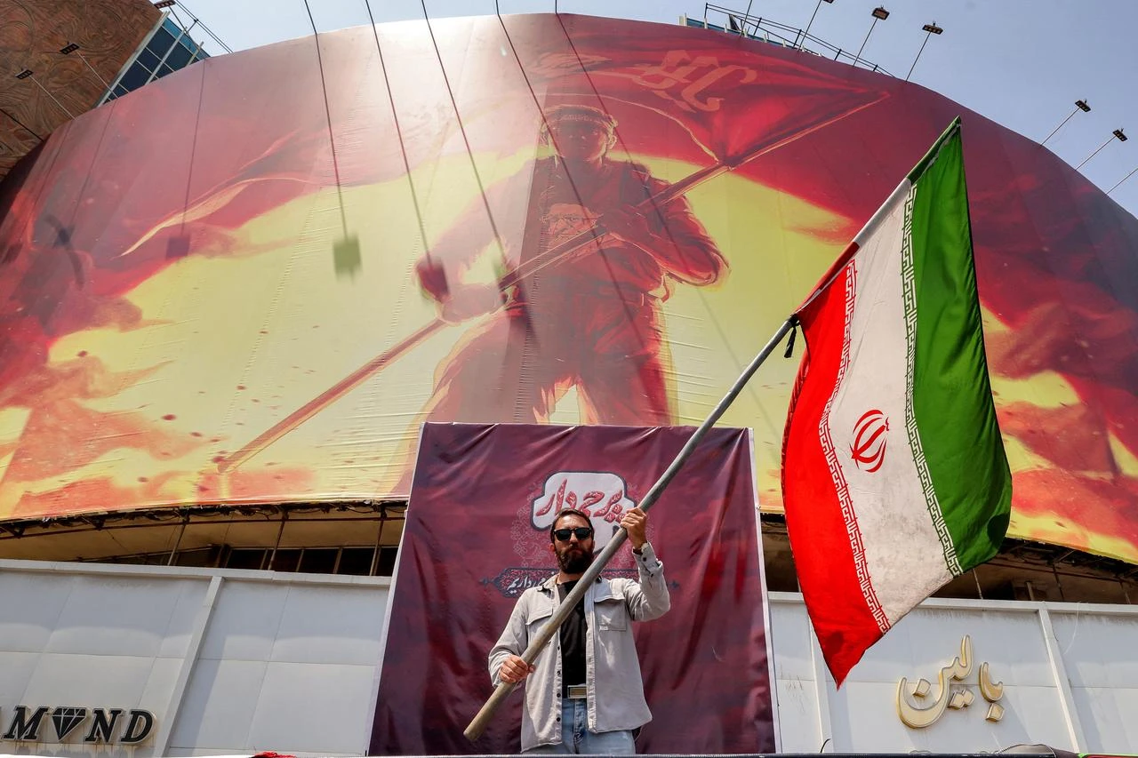 A man waves an Iranian flag before a political billboard at Valiasr Square in central Tehran on August 8, 2026. (AFP Photo)