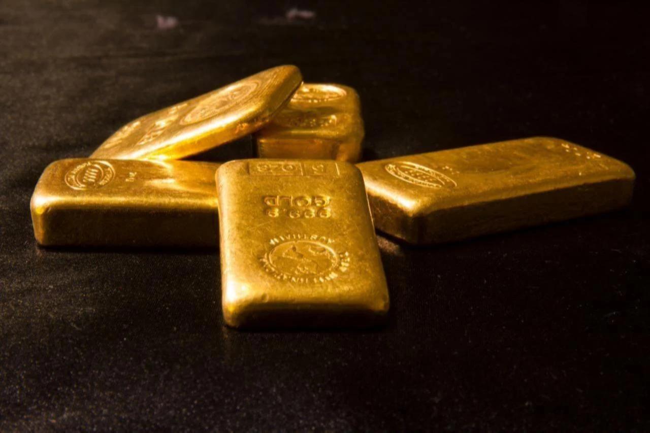 Gold bars displayed on a dark surface. (Adobe Stock Photo)