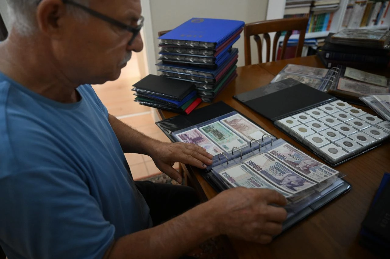 Selami Yilmaz posing next to his collection featuring currencies from 163 countries over the years. (AA Photo)