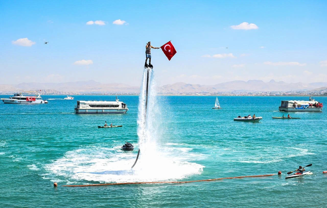 A flyboard performer holds a Turkish flag above Lake Van during the 12th Lake Van Water Sports Festival in eastern Türkiye, Aug. 8, 2026. (AA Photo)
