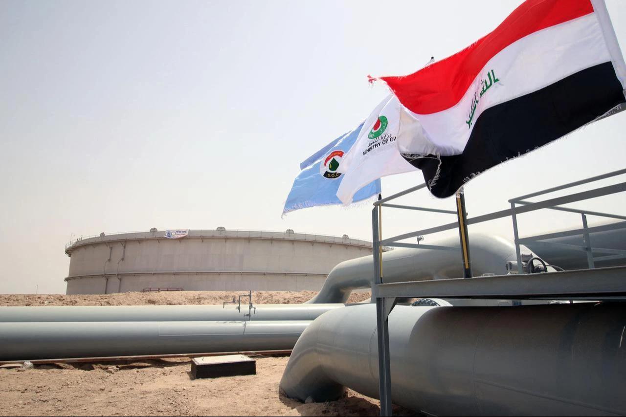 A picture taken on May 31, 2015 shows Iraqi flags fluttering in front of a tank for oil at al-Fao (also spelled al-Faw) storage terminal, located on the al-Fao Peninsula, south of the Iraqi province of Basra. (AFP File Photo)