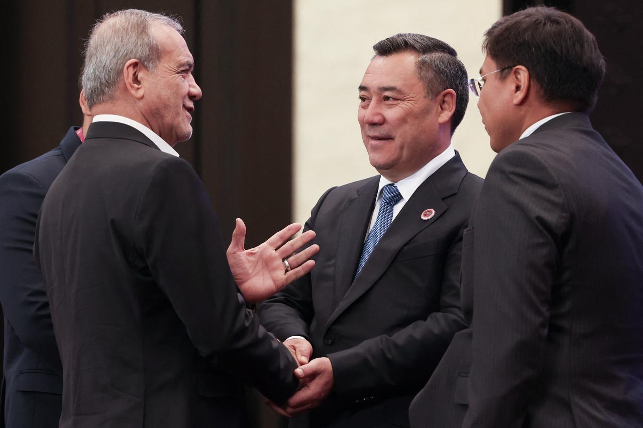 In this pool photograph distributed by the Russian state agency Sputnik, Kyrgyzstan's President Sadyr Japarov welcomes Iran's President Masoud Pezeshkian prior to the Shanghai Cooperation Organisation (SCO) summit in Bishkek on September 1, 2026. (Photo by Sputnik / AFP)