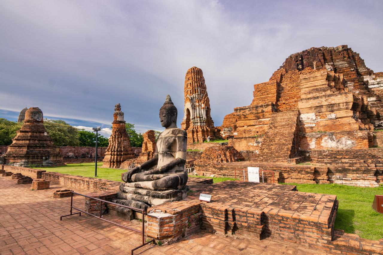 A seated Buddha statue stands among the historic temple ruins of Ayutthaya, Thailand. (Adobe Stock Photo)