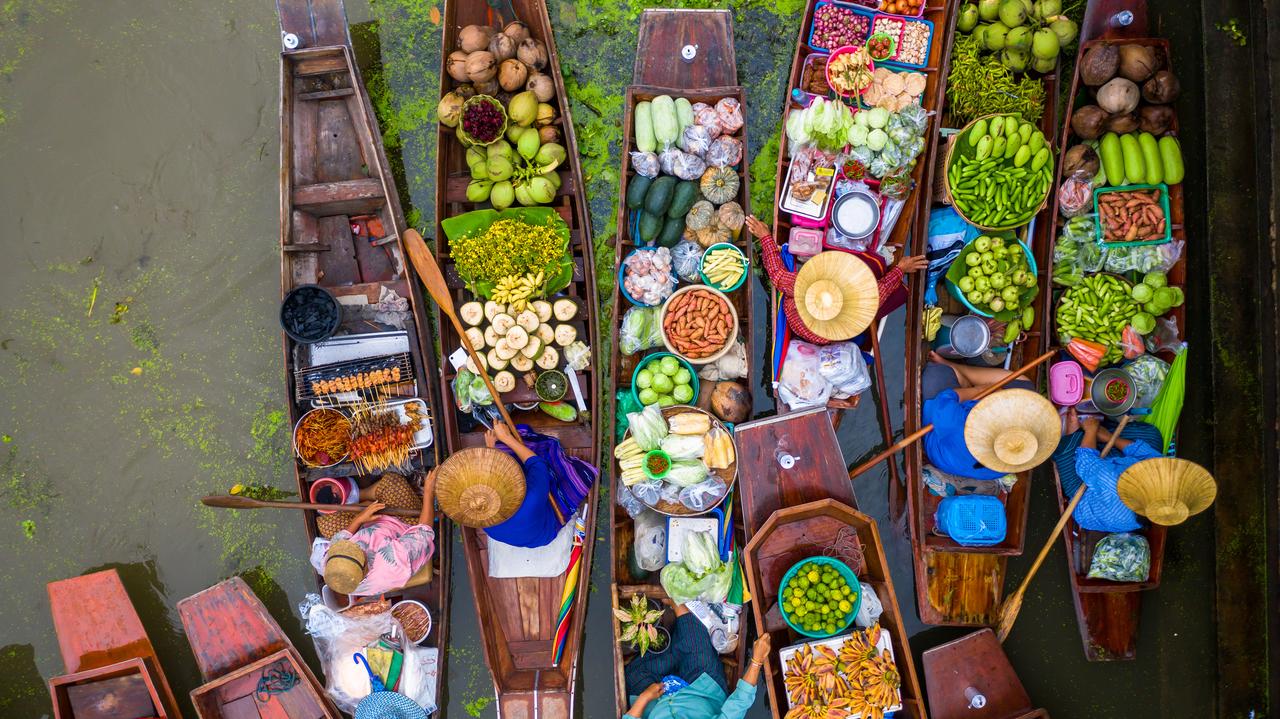 Vendors sell fresh produce and food from wooden boats at a floating market in Thailand. (Adobe Stock Photo)