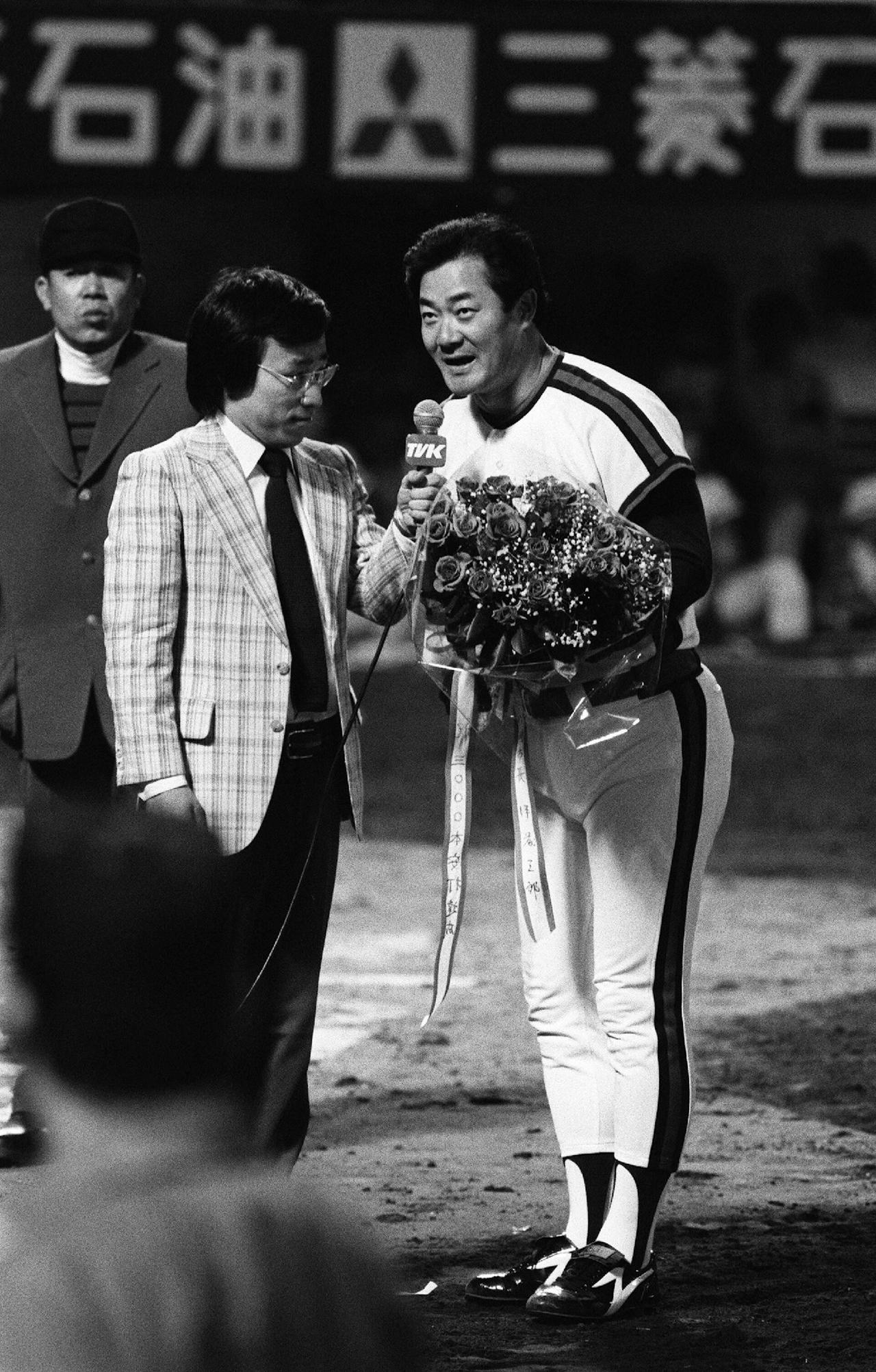 Former Japanese baseball player Isao Hairmoto (R) speaks into a microphone while holding a bouquet during a ceremony in Tokyo, Japan. (AFP Photo)