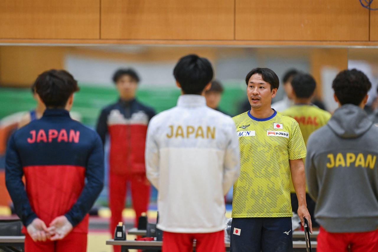 A member of the coaching staff speaks to members of the Japan gymnastics team as they hold an training exhibition for the media ahead of the Aichi-Nagoya Asian Games in Tokyo on September 9, 2026. (AFP Photo)