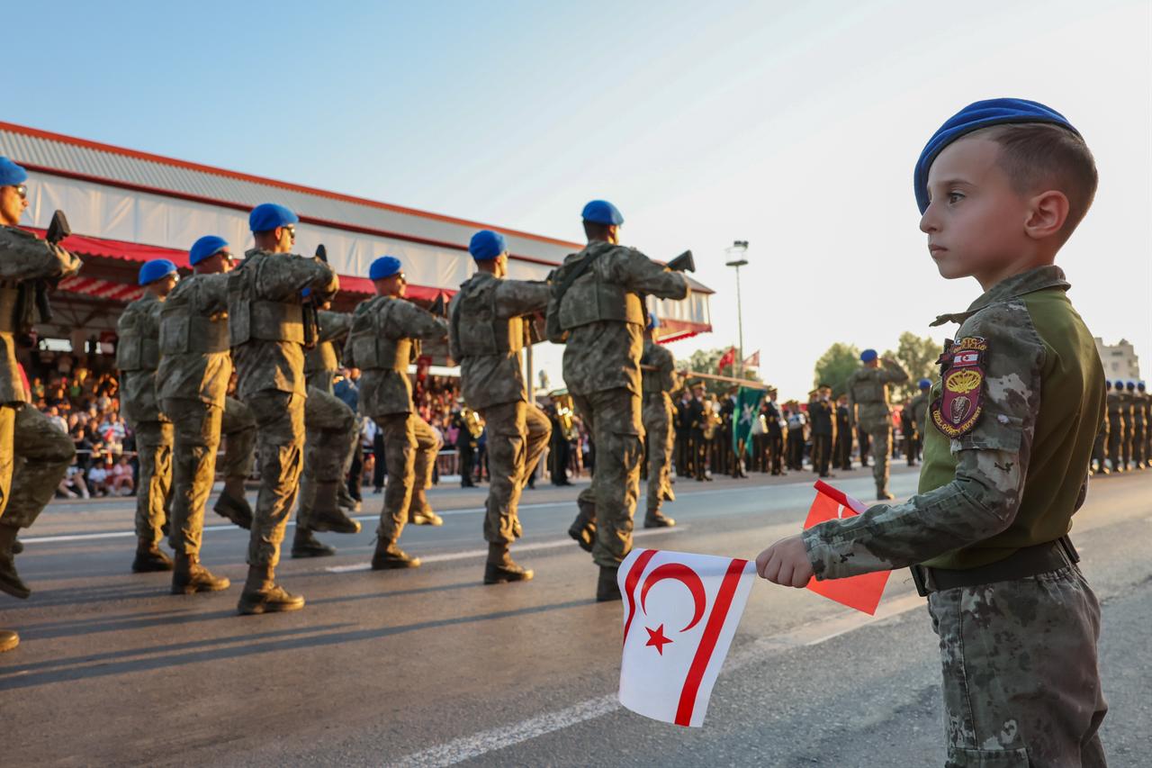 A child holding Turkish and Turkish Republic of Northern Cyprus (TRNC) flags watches Turkish soldiers march during a military parade marking Peace and Freedom Day on Dr. Fazil Kucuk Boulevard in the TRNC, July 20, 2026. (AA Photo)