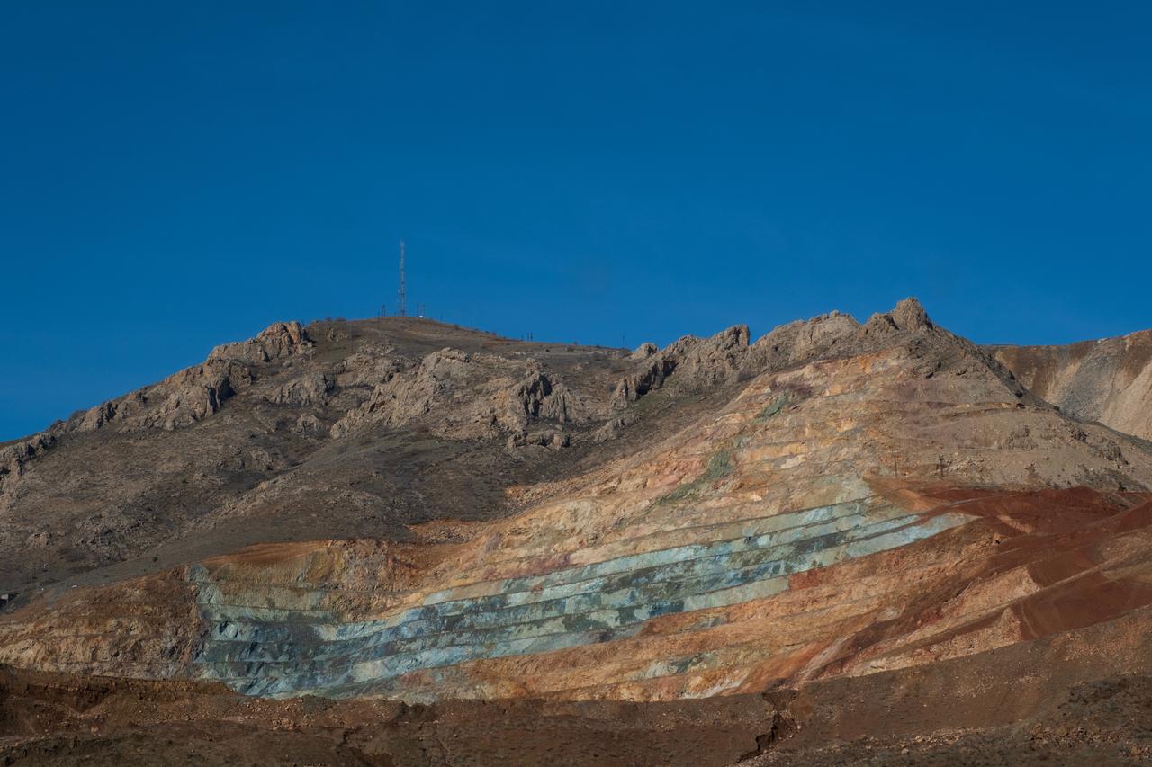 Exposed mineral-rich rock layers stretch across the terraced mining site at an open-pit iron ore mine in Divrigi, Sivas, Türkiye. (Adobe Stock Photo)