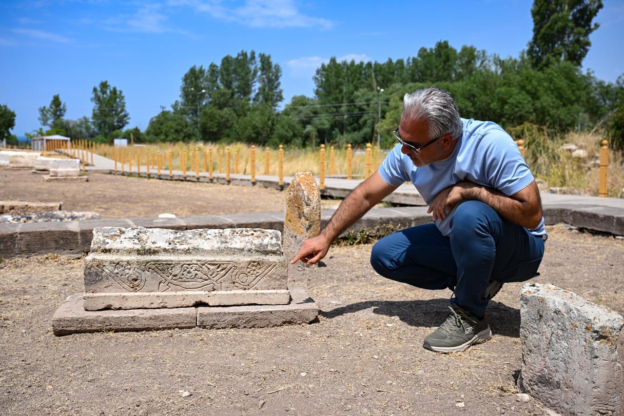 Professor Ercan Calis examining the newly uncovered children's gravestone with a chevgan motif at the historic Seljuk Cemetery in the Gevas district of Van. (AA Photo)