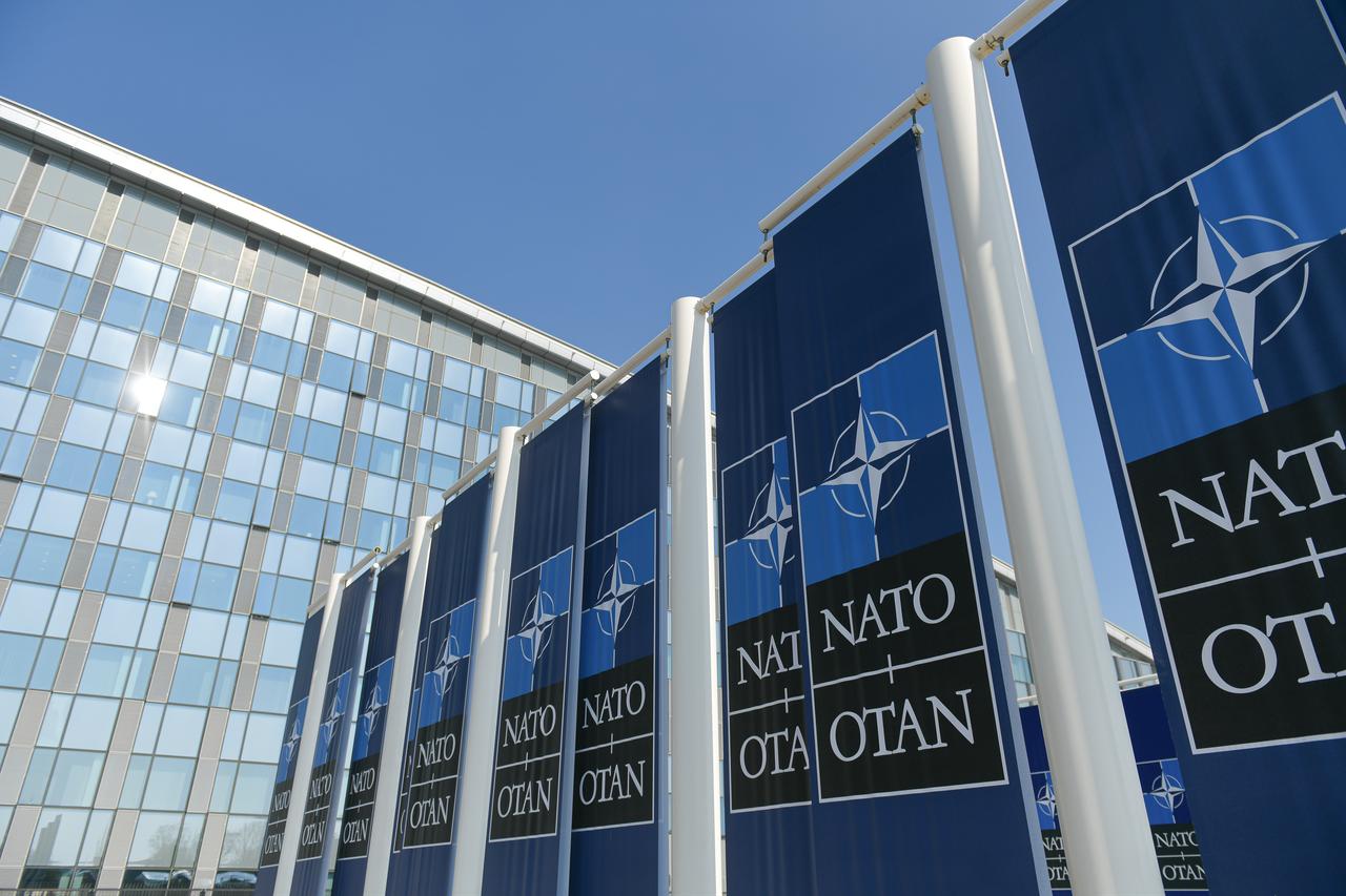 NATO logo flags in front of the headquarters building in Brussels, Belgium, 2022. (Photo via Adobe Stock)