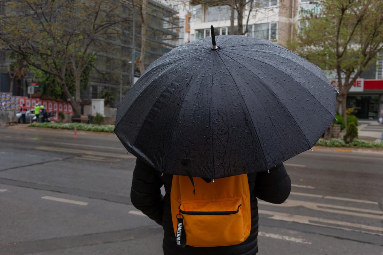 A pedestrian walks under an umbrella on a rain-soaked street in Ankara, Türkiye. (Adobe Stock Photo)