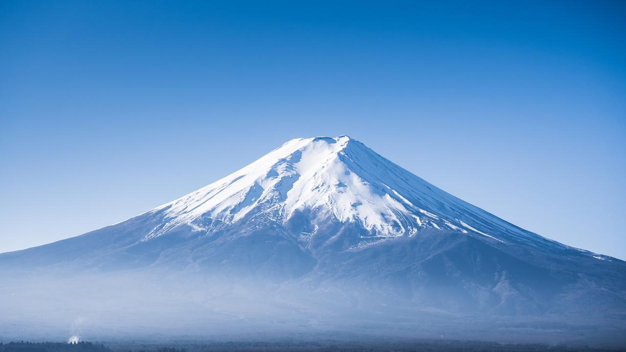 Snow-covered Mount Fuji rises beneath a clear blue sky in Japan. (Adobe Stock Photo)