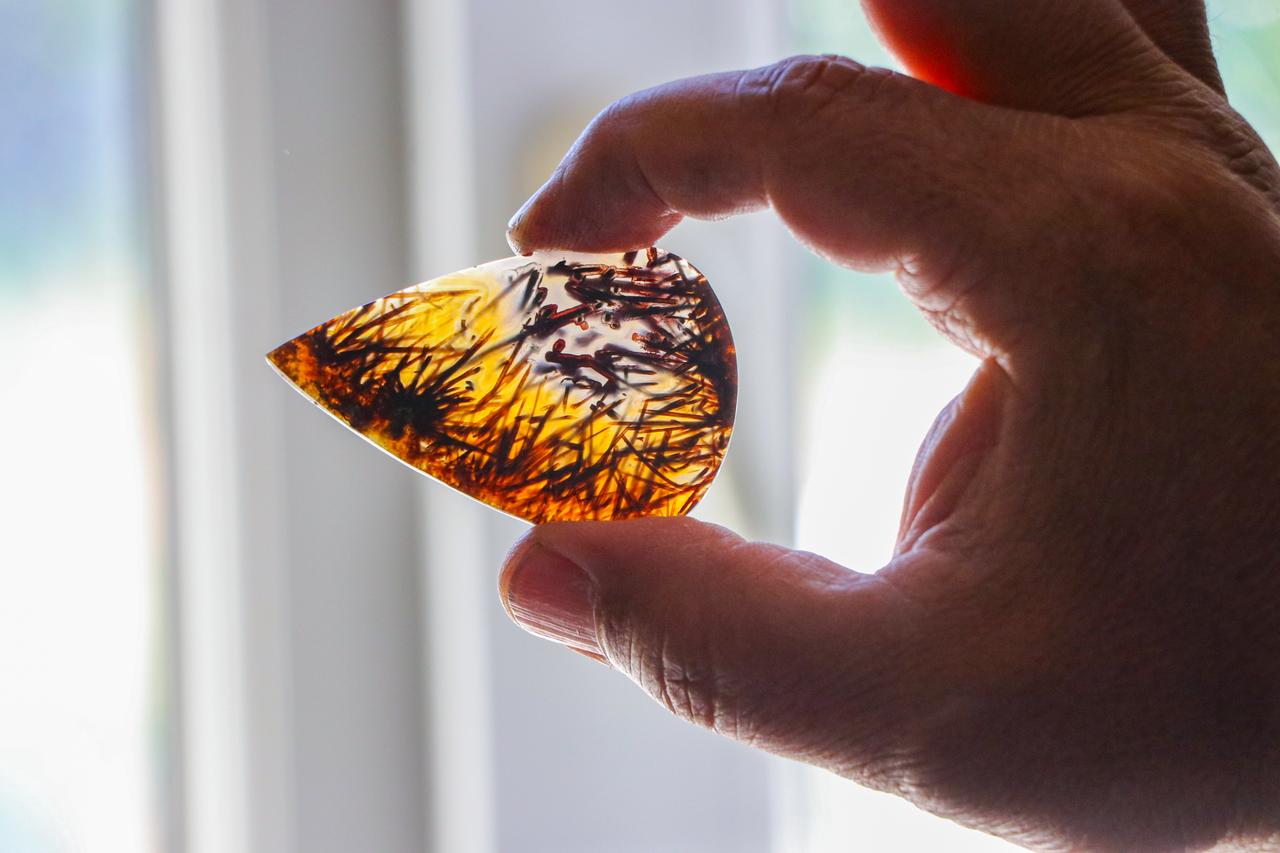A close-up view shows a polished stone featuring natural dendritic inclusions held against the light by sculptor Erol Gurses in the Aydincik district of Yozgat, Türkiye, Sept. 16, 2026. (AA Photo)