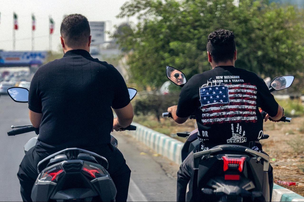A motorist wearing an anti-US shirt rides a scooter next to another motorist along a street in Tehran on September 9, 2026. (AFP Photo)