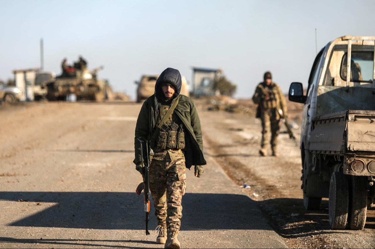 Soldiers walk past a parked car as Syrian government forces make their way to the city of al-Hasakah in northeastern Syria on January 20, 2026. (AFP Photo)