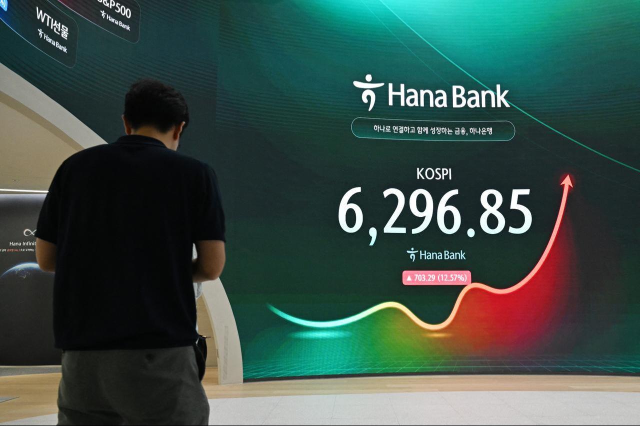 A man stands near an electronic screen showing South Korea's benchmark stock index (KOSPI) outside a foreign exchange dealing room at the Hana Bank headquarters in Seoul, July 31, 2026. (AFP Photo)