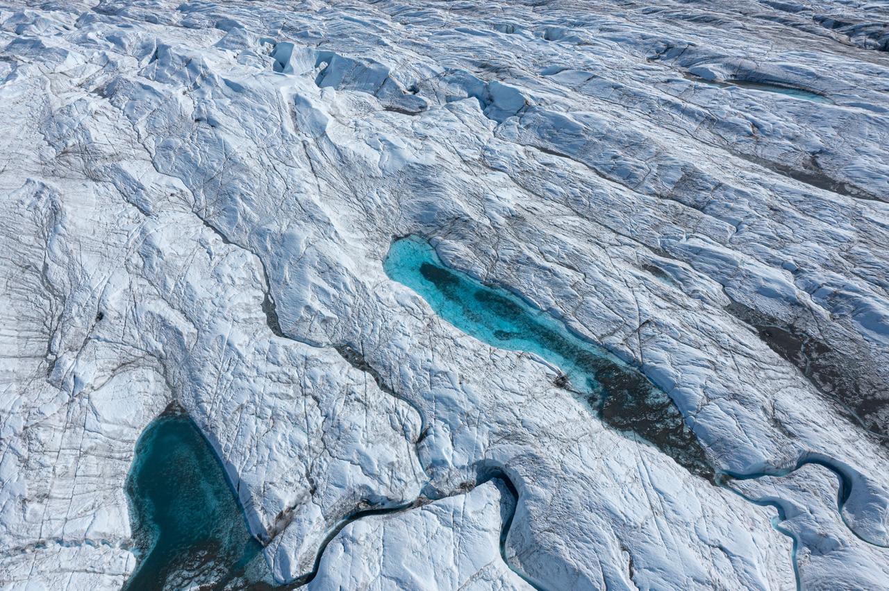 Meltwater pools and channels form across the surface of a glacier, highlighting accelerating ice loss linked to climate change. (Adobe Stock Photo)