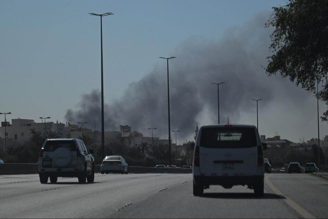 Motorists drive along a street as smoke rises from a reported Iranian strike in the area where the US Embassy is located in Kuwait City on March 2, 2026. (AA Photo)