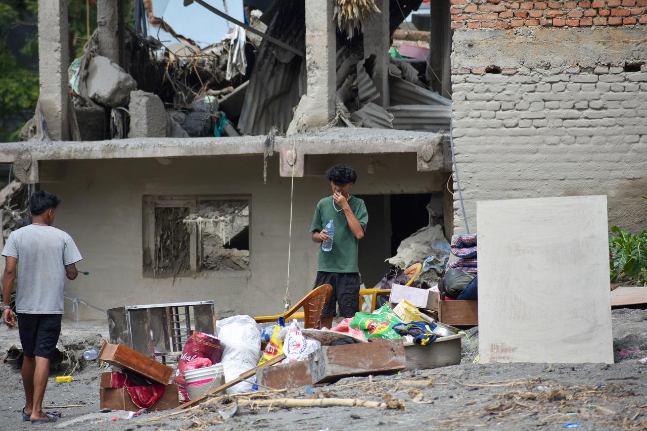 Residents stand among belongings and debris outside a flood-damaged building in Nuwakot, Nepal, Sept. 1, 2026. (AA Photo)