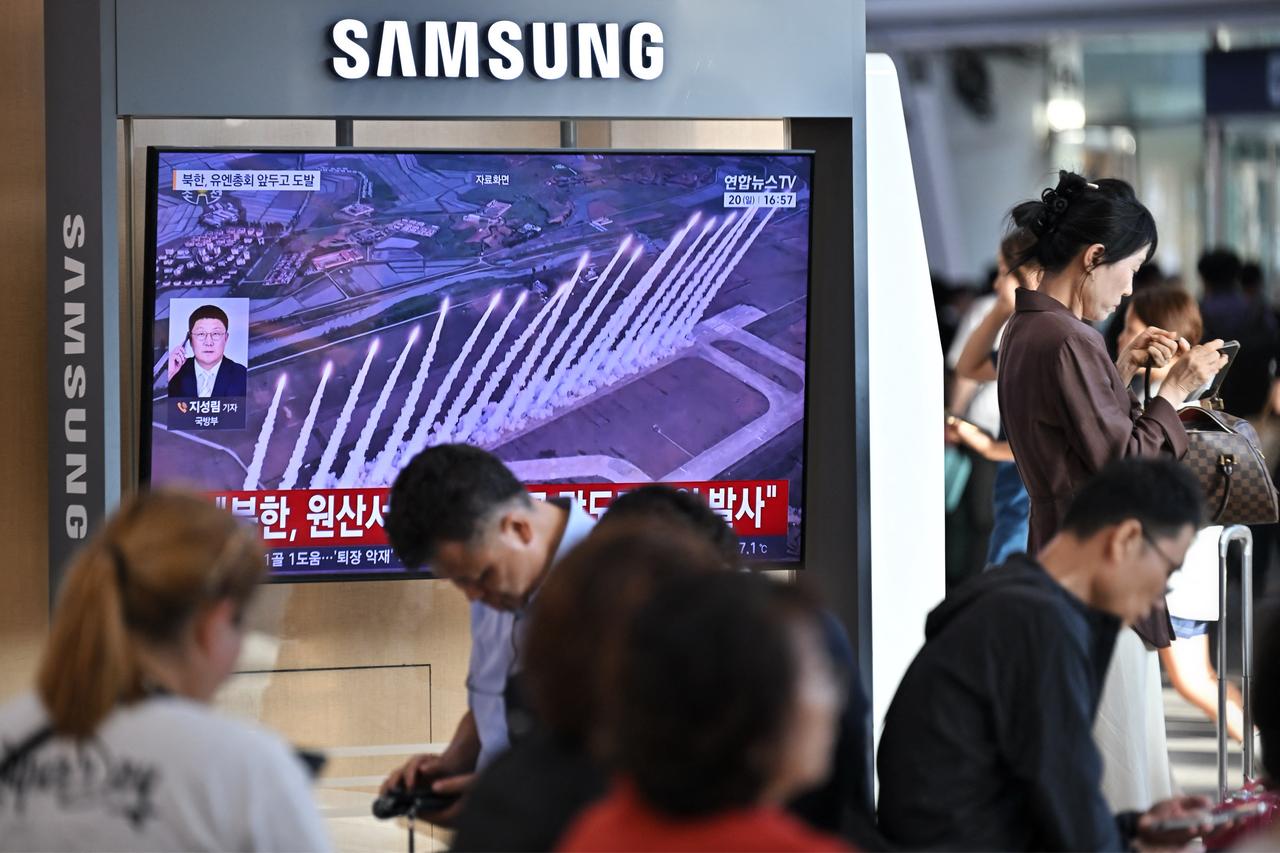 People sit near a television screen showing a news broadcast with file footage of a North Korean missile test, at a train station in Seoul on September 20, 2026. (AFP Photo)