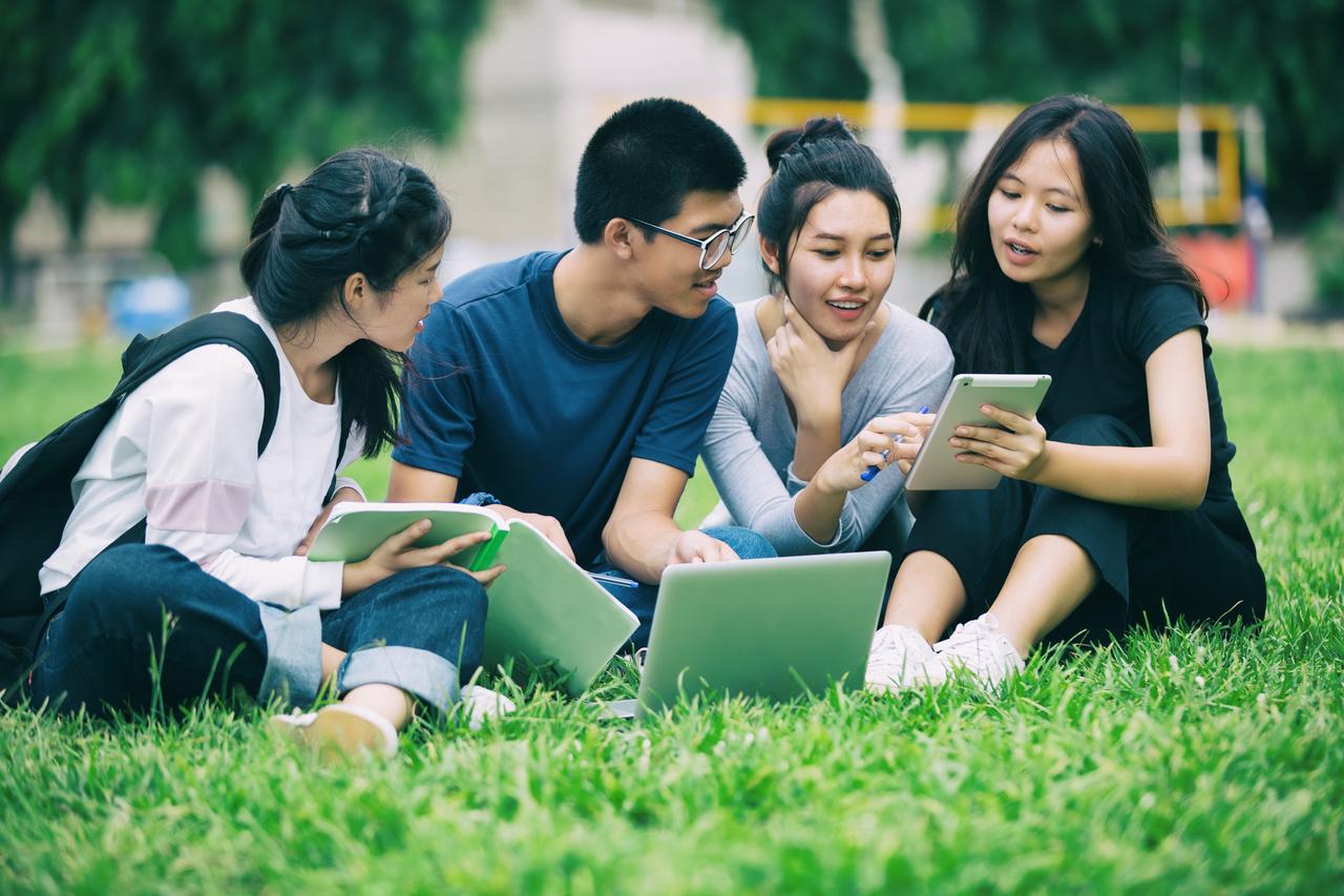 Asian Group of students sharing with the ideas for working on the campus lawn. (Adobe Stock Photo)