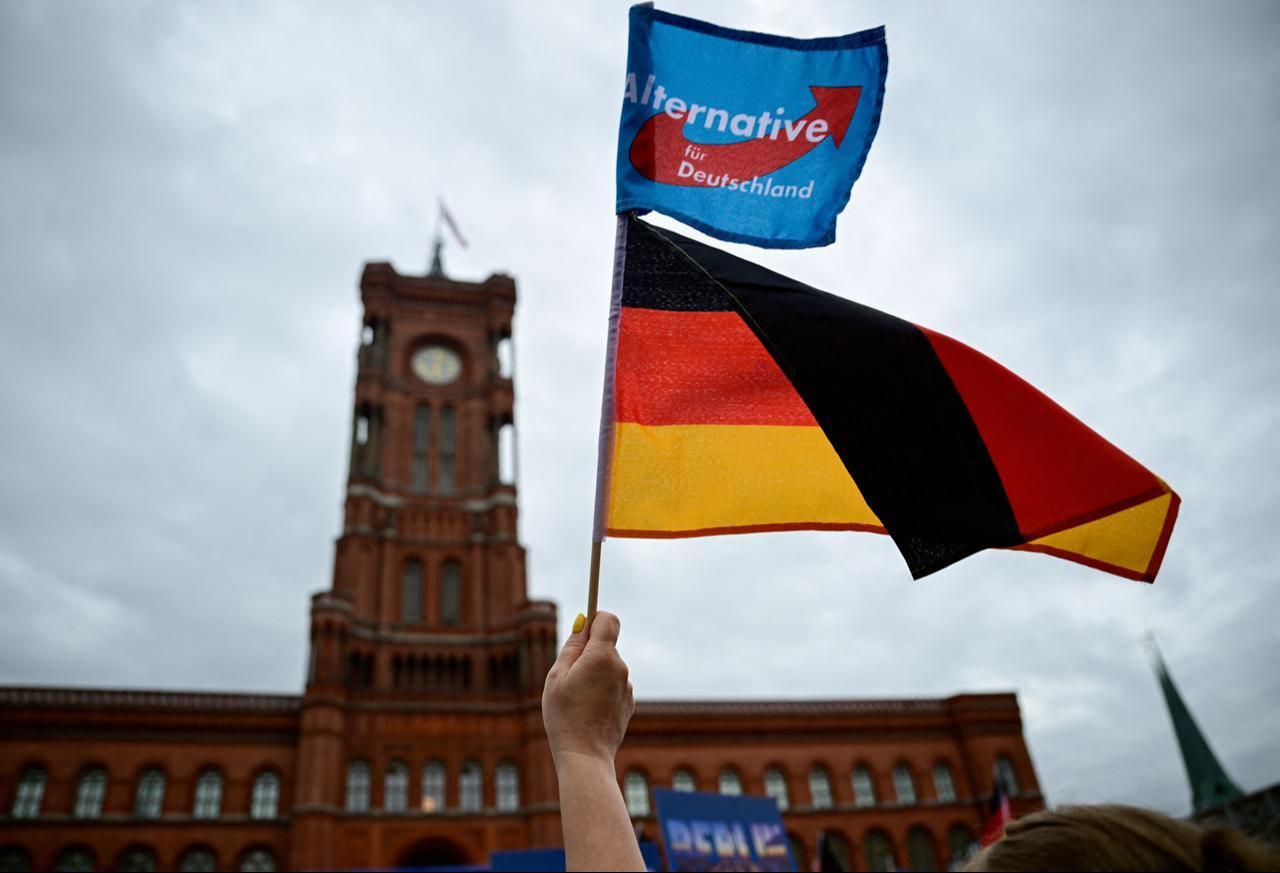 A supporter of the far-right Alternative for Germany (AfD) party waves their party's flag and a German flag at a campaign rally in front of the Berlin City Hall, June 29, 2026. (AFP Photo)