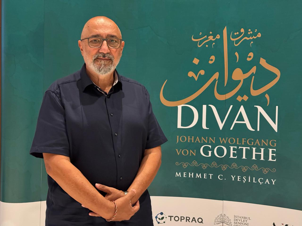 Composer and artistic director Mehmet C. Yesilcay poses beside a poster for Goethe's "West-Eastern Divan" at the Ataturk Cultural Center in Istanbul, Türkiye. (AA Photo)