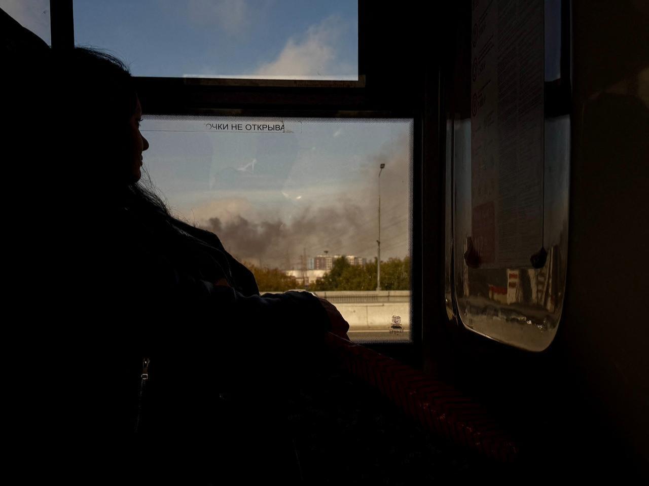 A woman rides in a bus as smoke rises from the area of the Russian oil producer Gazprom Neft's Moscow oil refinery in Moscow on September 20, 2026. (AFP Photo)