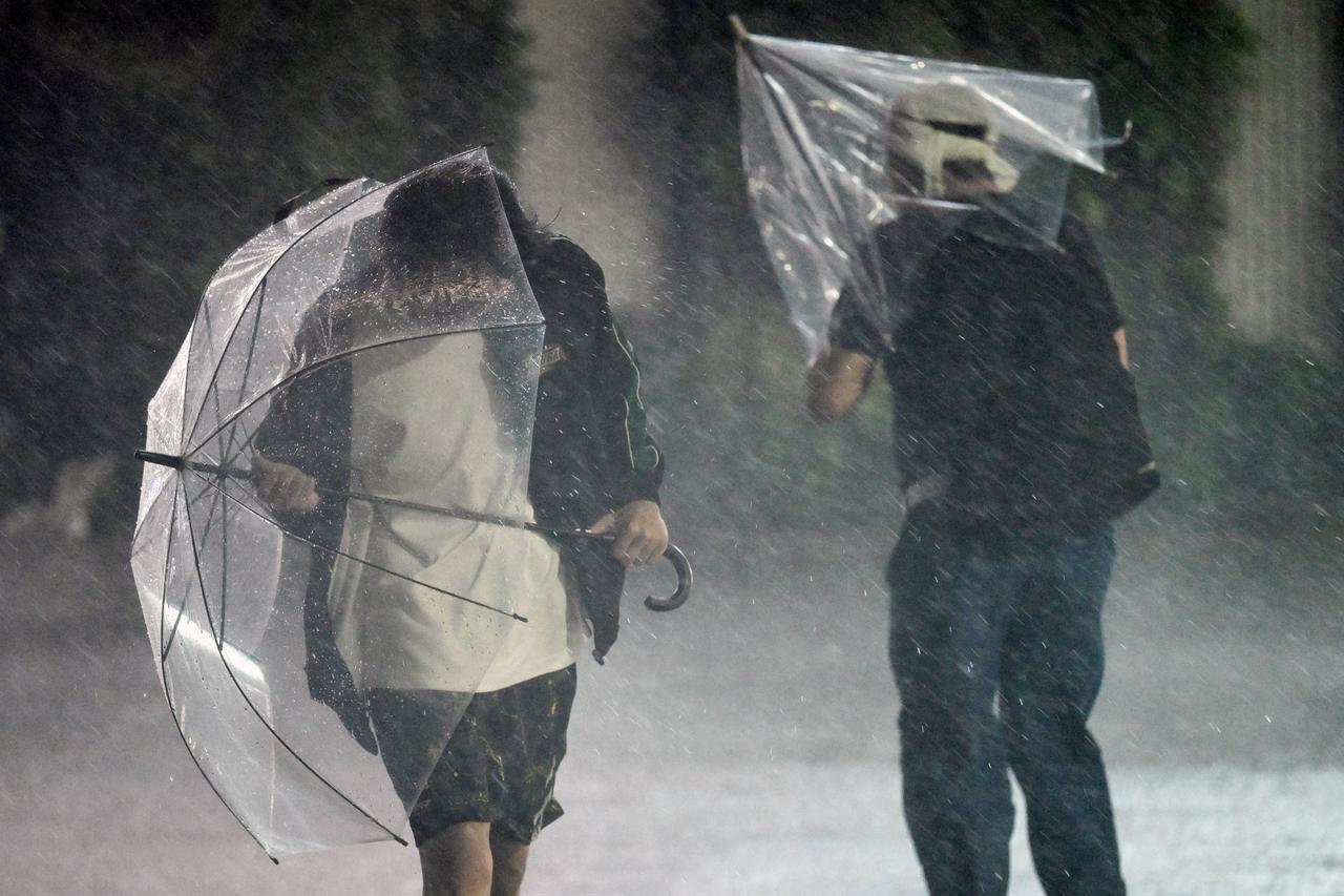 Pedestrians hold on to their umbrellas amid strong winds and heavy rainfall in Chiba on September 21, 2026.(AFP Photo)