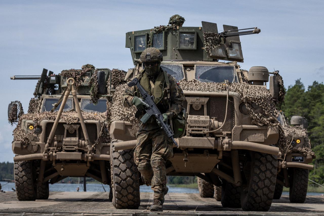 A Polish soldier is seen in front of two Lithuanian Armed Forces Oshkosh JLTVs on the deck of a Polish Army PFM Motorized Floating Bridge during a lake crossing in the Amber military exercise, June 24, 2026. (AFP Photo)