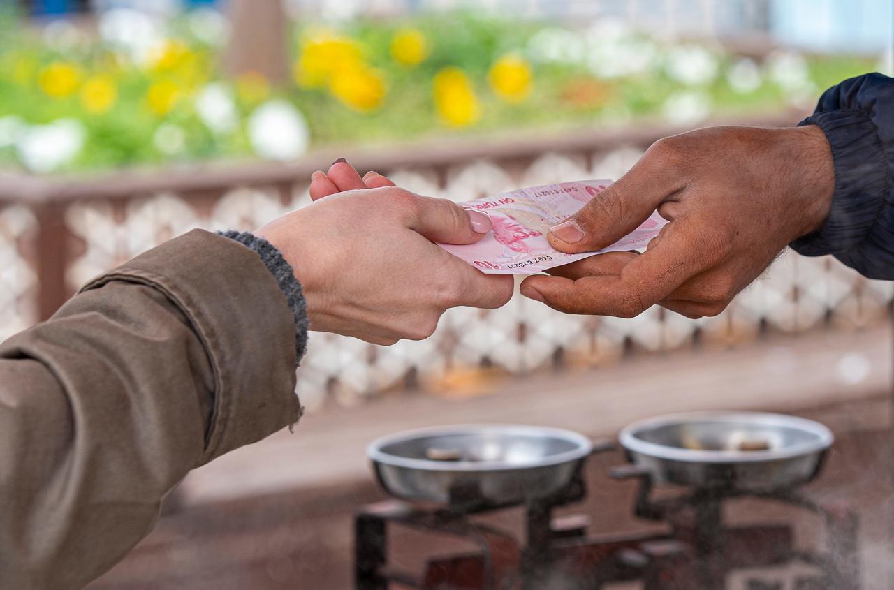 A customer hands a Turkish lira banknote to a street food vendor in Istanbul. (Adobe Stock Photo)