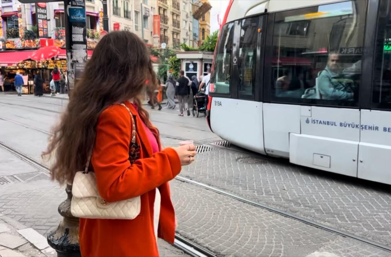 Aya waits beside an Istanbul tram in 2024. For her, freedom in the city came to mean being able to move without calculating checkpoints into every journey. (Photo courtesy of Aya)