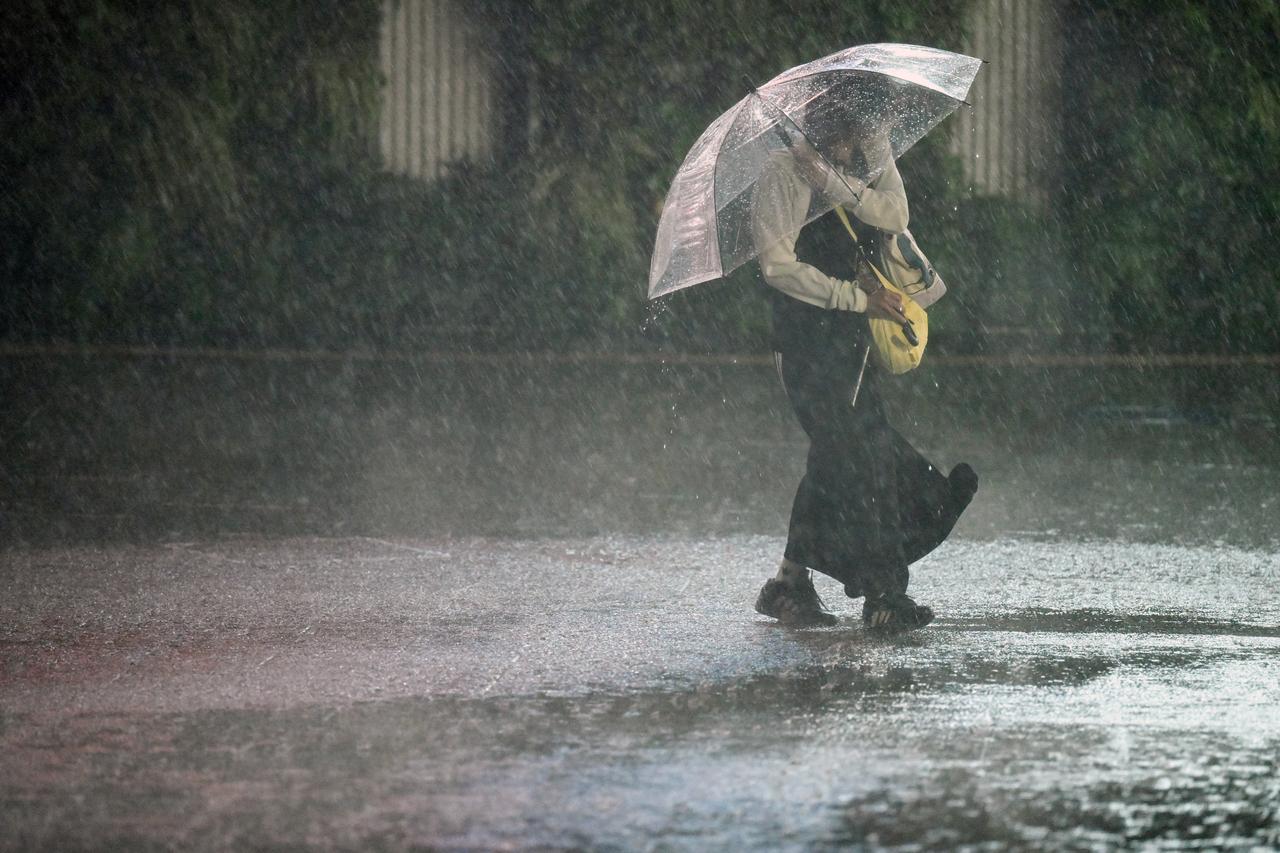 A pedestrian with an umbrella walks down a street in Chiba amid heavy rainfall on September 21, 2026. (AFP Photo)