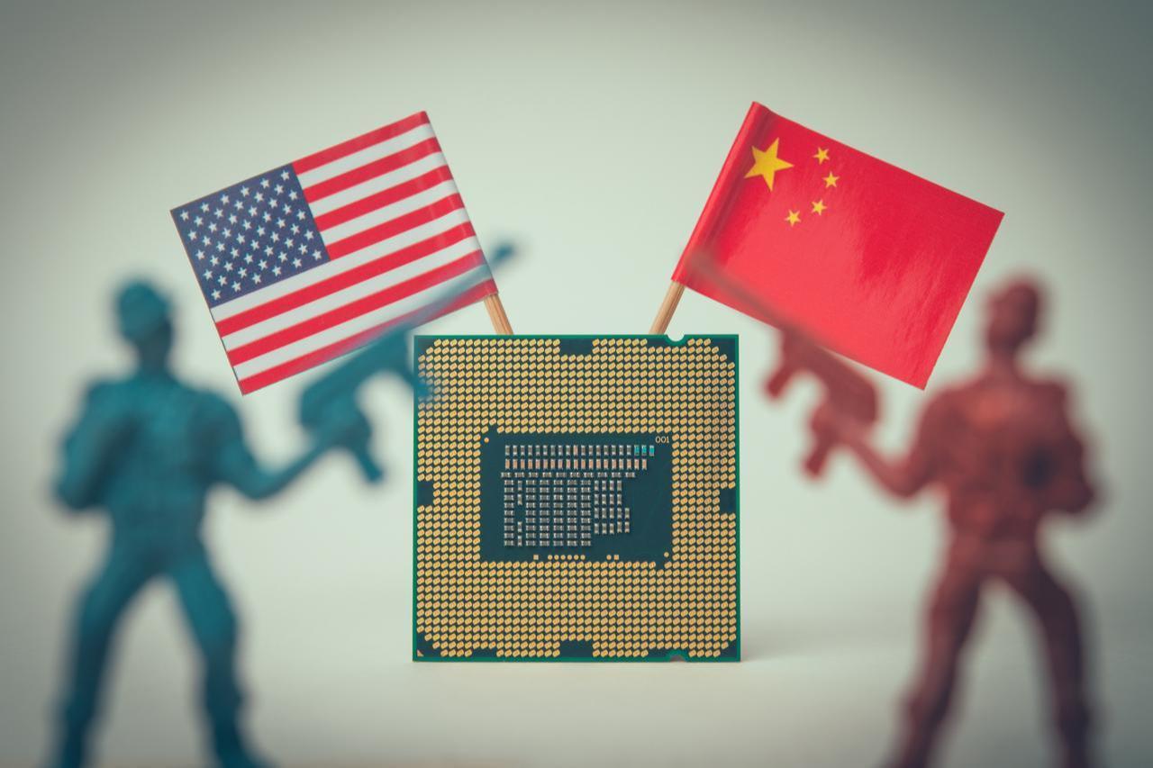 U.S. and Chinese flags are displayed behind a semiconductor chip in an illustration representing technology and chip competition between the two countries. (Photo via Adobe Stock)
