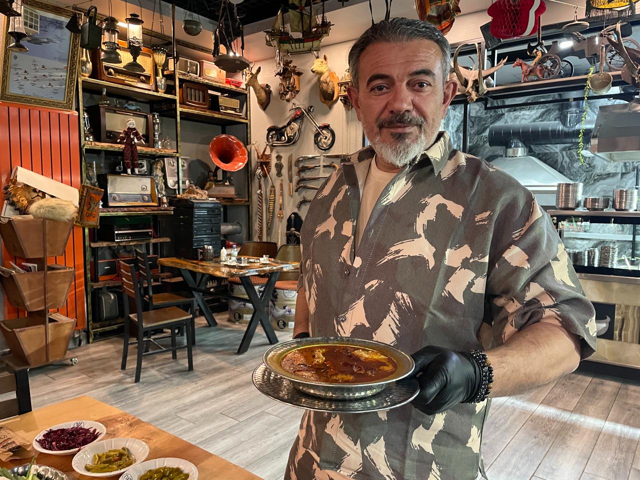 Ramazan Bademci holds a freshly prepared bowl of "atom" soup at his shop in Konya, Türkiye. (IHA Photo)